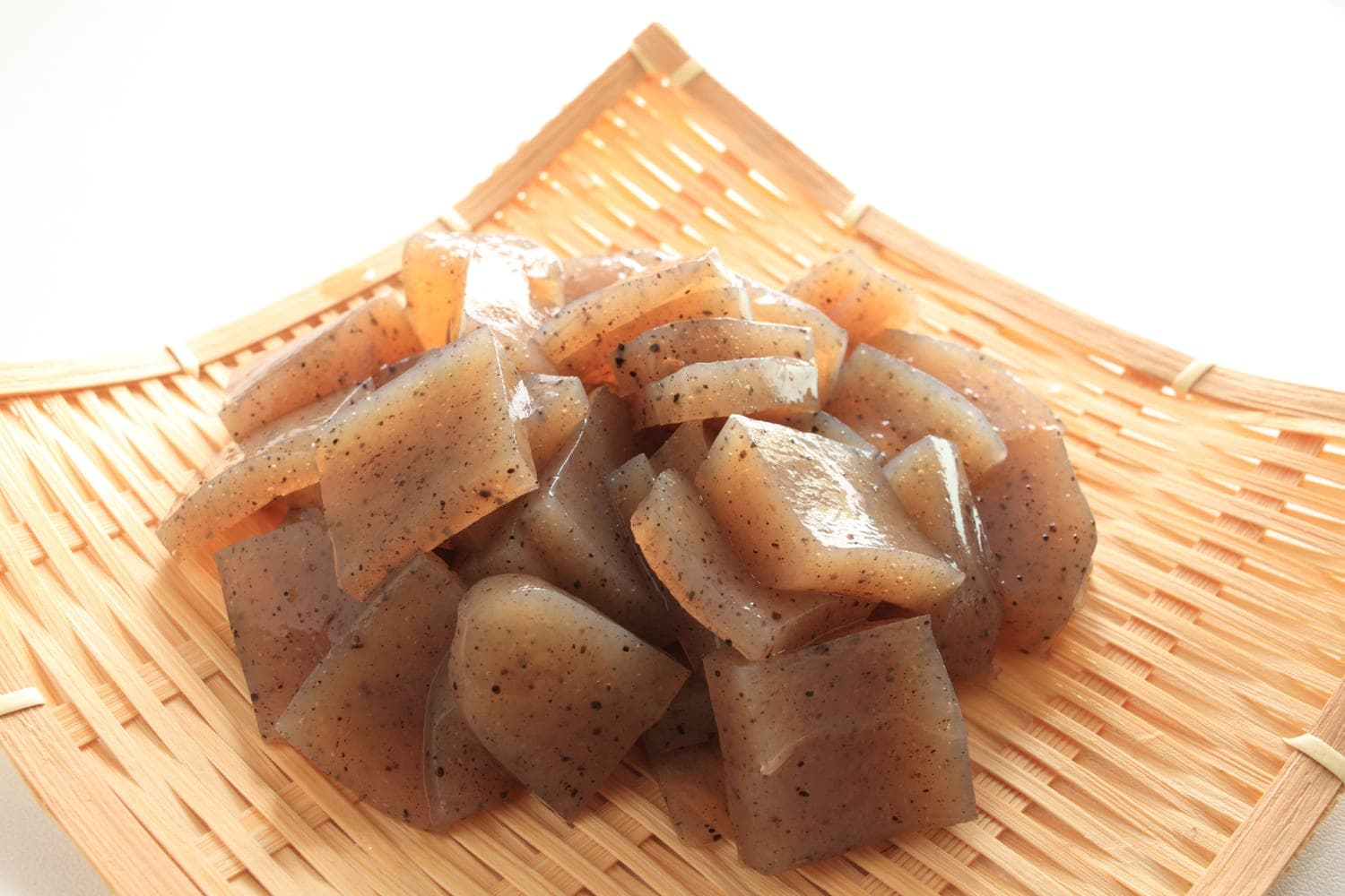 Pieces of konjac jelly piled on a woven bamboo tray.